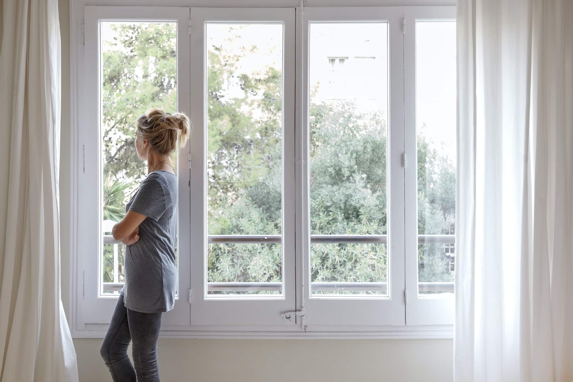 Woman at home, looking out of window